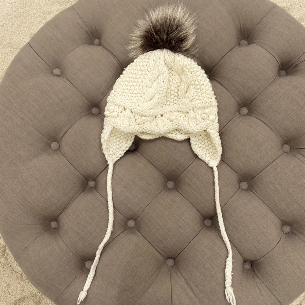 Ivory knit beanie with ear flap and gray raccoon pom